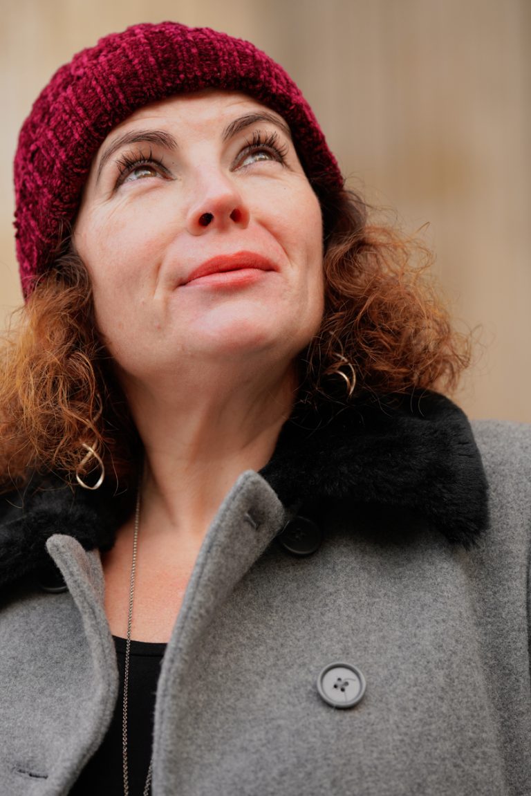Close Up Portrait Of British Woman In Grey Coat, Red Hat with St. Paul’s Cathedral, London, Winter Daytime Low Angle Shot