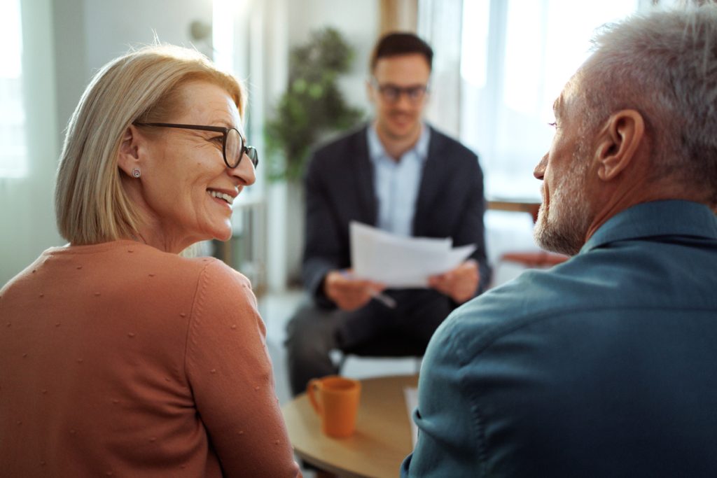 Rear view of mature couple having meeting with insurance agent at their home