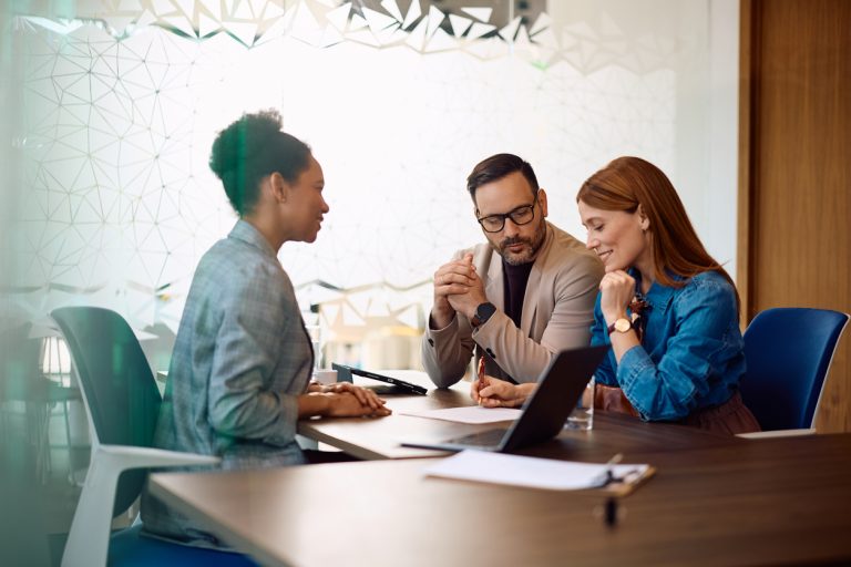Smiling couple signing paperwork after successful consultations with their insurance agent in the office.